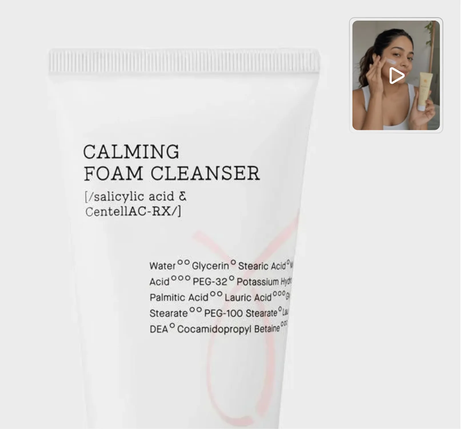 A face cleanser on a grey background, with a video button in the top corner, a thumbnail of someone trying the product with a play icon over it.