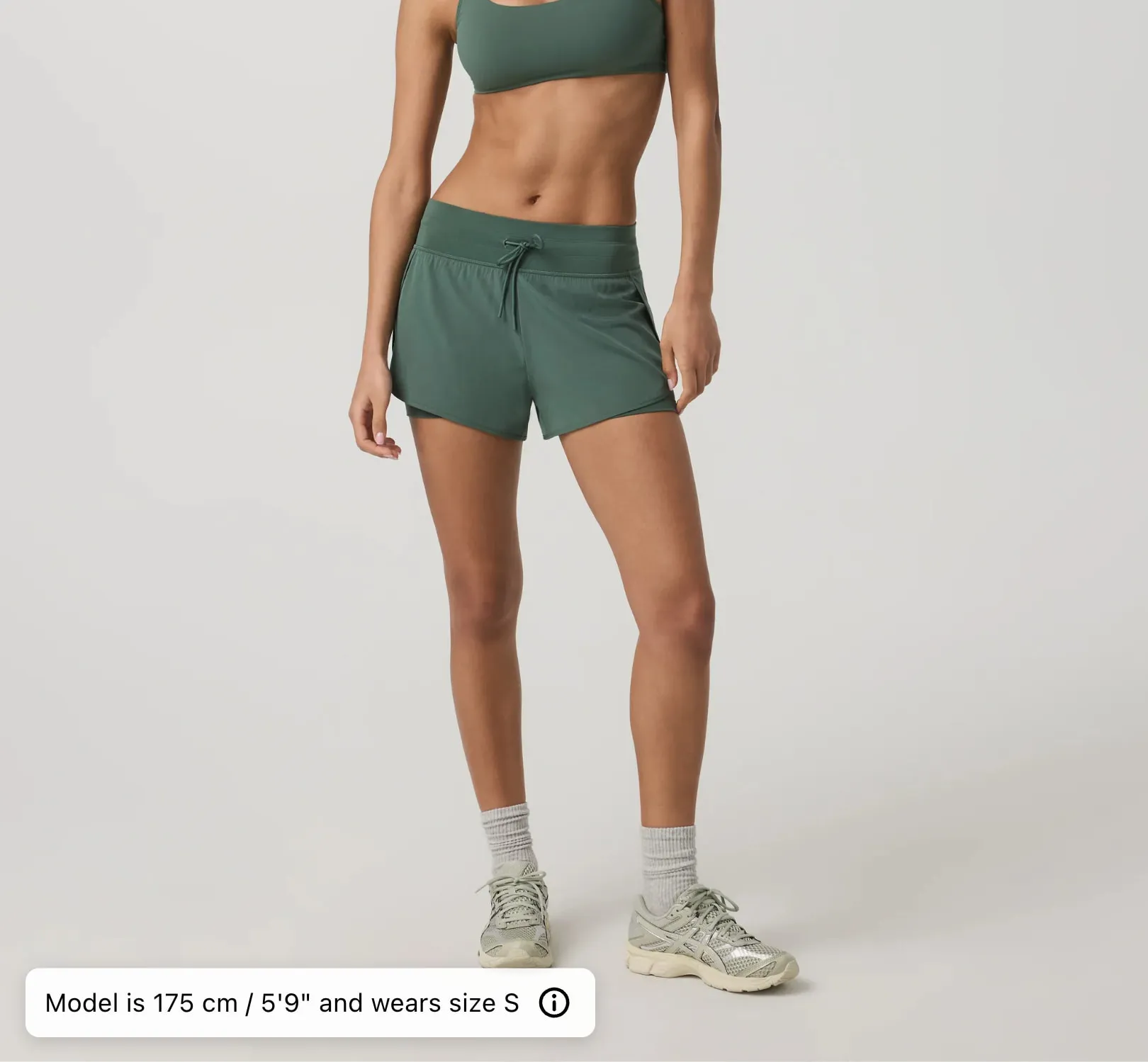 A model in green running shorts, with a caption along the bottom giving the model’s height, 175 cm, and the size worn, S.